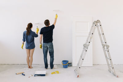 A young couple in love have moved into a new house and are making repairs painting white walls