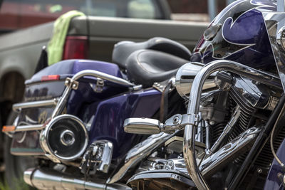 Close-up of motorcycle parked against vintage car