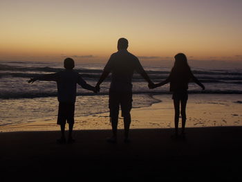 Silhouette of people on beach at sunset