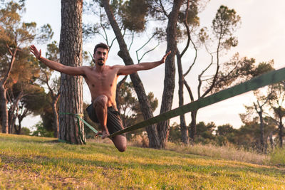 Man with arms outstretched doing slacklining during sunset