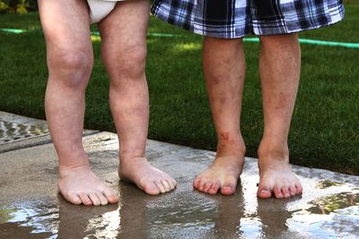 Low section of siblings standing on wet footpath