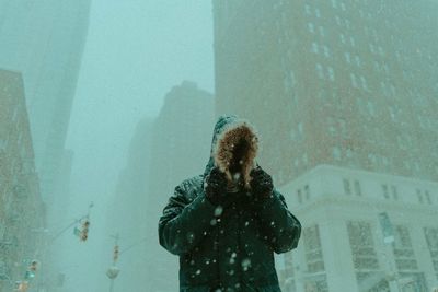 Low angle view of person standing in city during snowfall