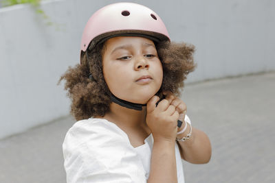 Girl with afro hairstyle adjusting sports helmet