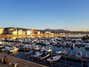 High angle view of boats moored at harbor against clear blue sky