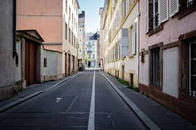 Empty road amidst buildings in city