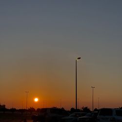 Cars on street against sky at sunset