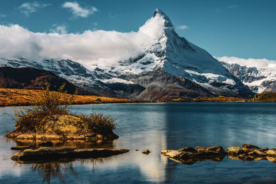 Scenic view of lake by snowcapped mountains against sky