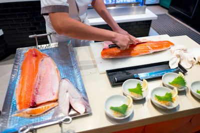 Midsection of man preparing fish in kitchen