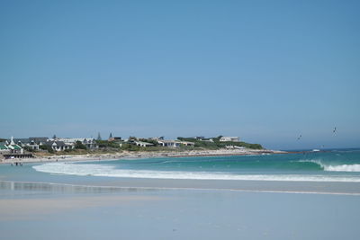 Scenic view of beach against clear blue sky