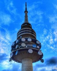 Low angle view of communications tower against cloudy sky