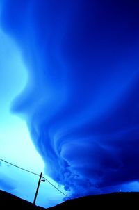 Low angle view of electricity pylon against blue sky