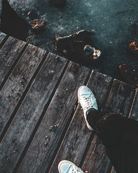 Low section of man standing on pier over lake