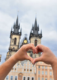 Cropped hands making heart shape against cathedral