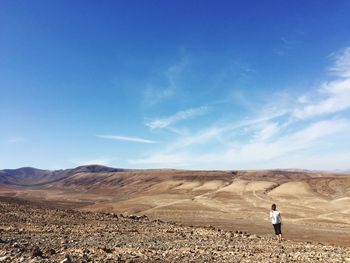 Rear view of woman standing on landscape against sky