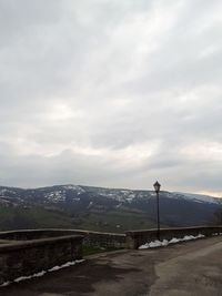 Road by mountains against sky