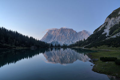 Scenic view of lake and mountains against clear blue sky