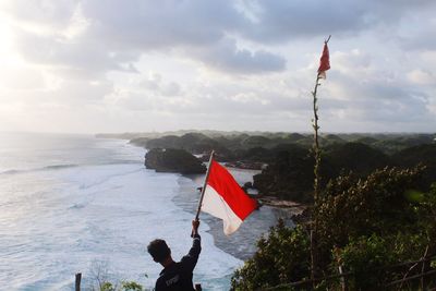 Red flag over sea against sky