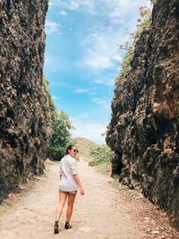 Woman standing on rock against sky