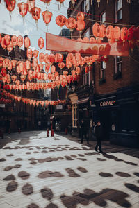 Illuminated lanterns hanging on street amidst buildings in city