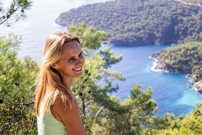 Side view of woman looking at sea against mountain