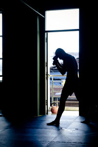 Silhouette man exercising by door