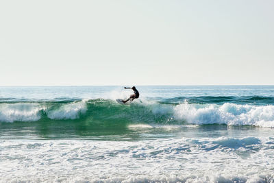 Man surfing in sea against clear sky