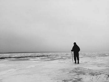 Man walking on frozen ice against sky