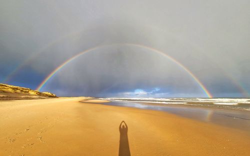 Scenic view of rainbow over sea against sky