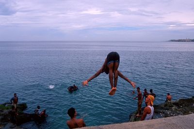 People swimming in sea against sky