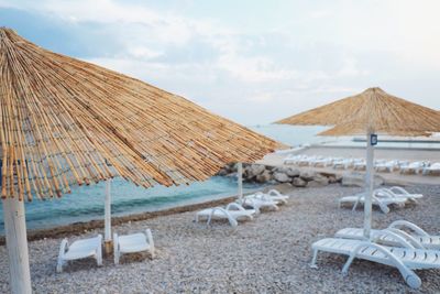 Deck chairs on beach against sky