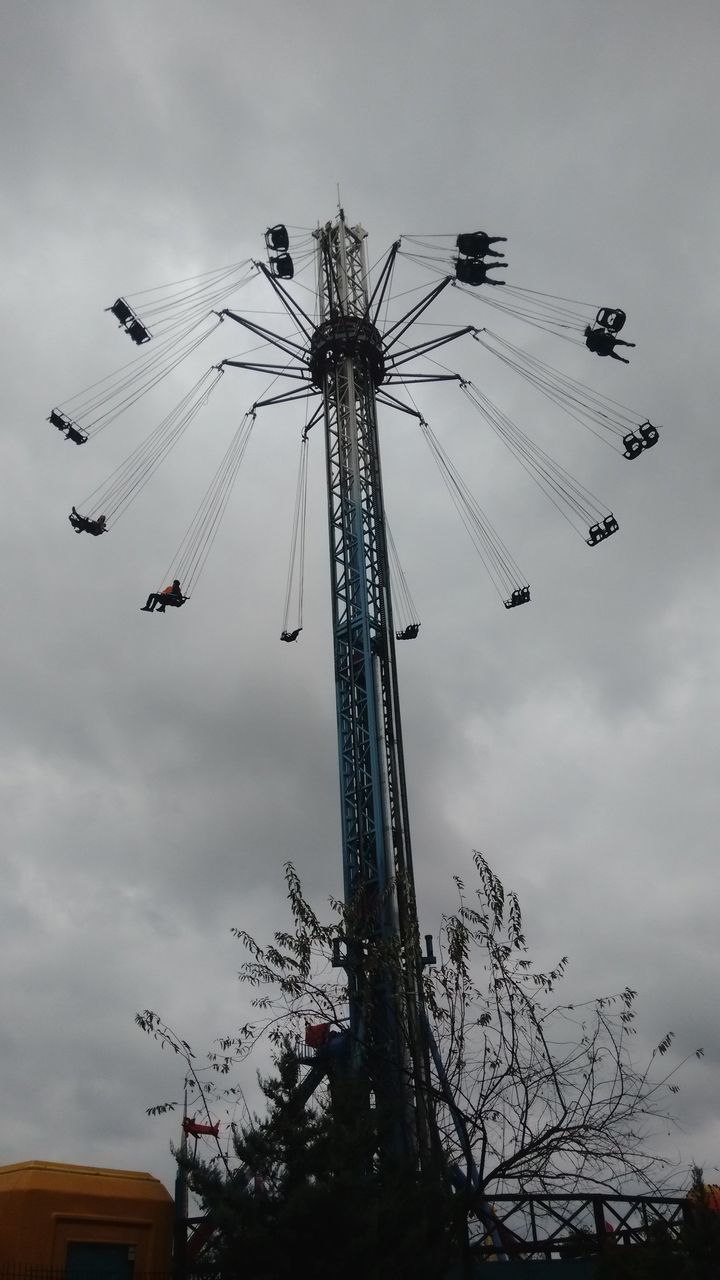 low angle view, sky, cloud - sky, cloudy, silhouette, arts culture and entertainment, built structure, cloud, amusement park, ferris wheel, building exterior, dusk, flying, amusement park ride, architecture, outdoors, overcast, windmill, chain swing ride, traditional windmill