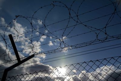 Low angle view of silhouette barbed wire fence against sky