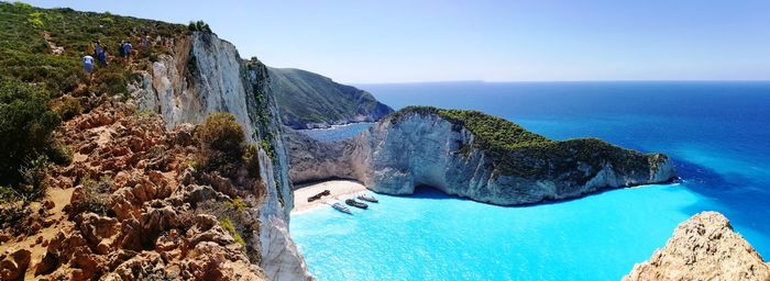 Panoramic shot of cliff by sea on beach against sky