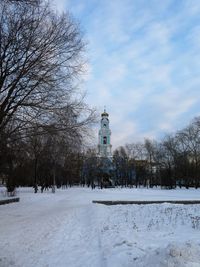Snow covered field by building against sky