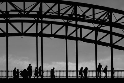 Silhouette people on bridge against sky