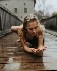 Young woman looking away while standing on wood