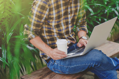 Midsection of man holding coffee cup