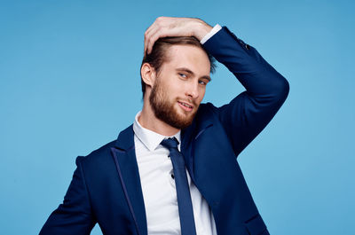 Portrait of young man standing against blue background