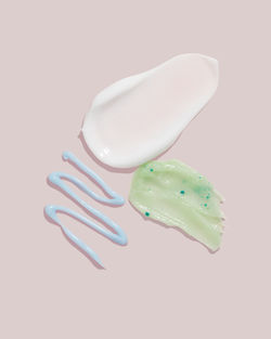 Composition of various cosmetic mask, cream or exfoliant smear on a pink background. 