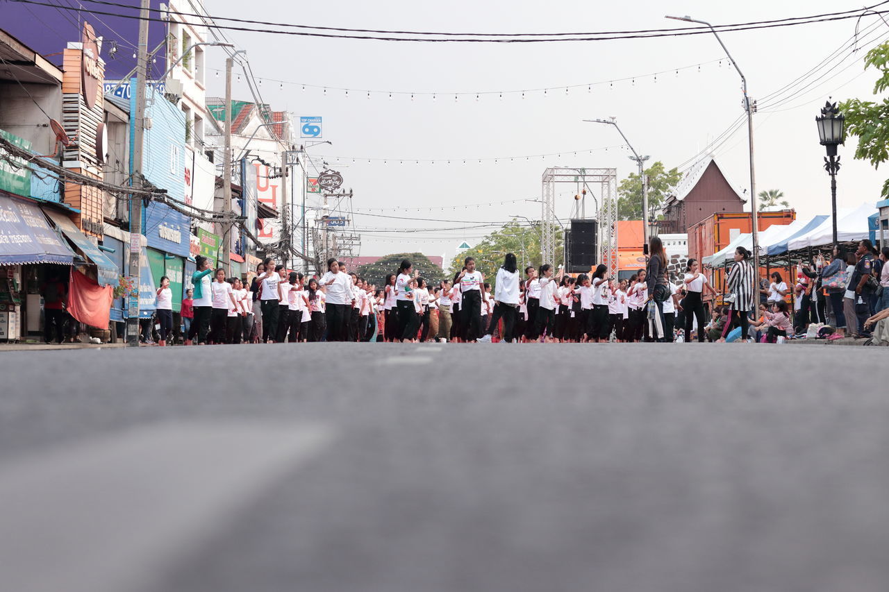 GROUP OF PEOPLE ON ROAD AGAINST BUILDINGS