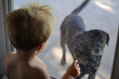 Rear view of shirtless man with dog in water