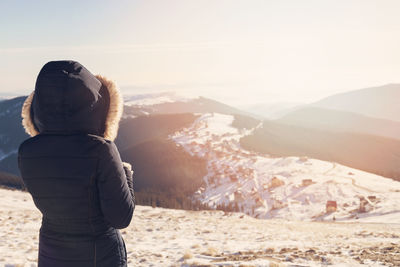 Rear view of woman looking at mountains during winter