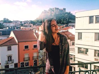 Young woman standing against buildings in city