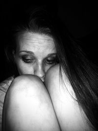 Close-up of depressed woman against black background