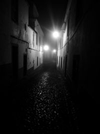 Walkway amidst illuminated buildings at night