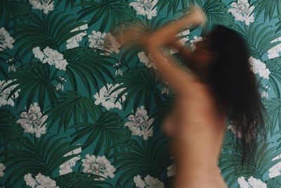 Blurred motion of shirtless woman against wall