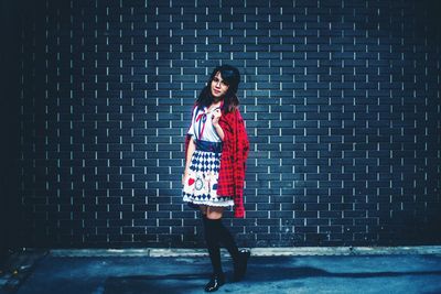 Portrait of woman standing against brick wall