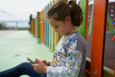 Little girl using smartphone on playground