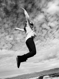 Low angle view of girl jumping against sky