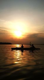 Silhouette people on sea against sky during sunset